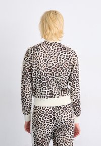 Leopard print sweatshirt in soft fabric with cream accents; ribbed cuffs and hem; fitted design with long sleeves.