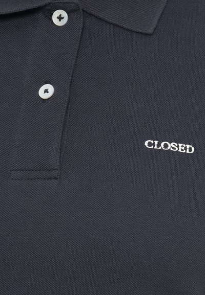 Σκούρο μπλε πουκάμισο πόλο με δύο λευκά κουμπιά και λευκό κεντημένο κείμενο "CLOSED" στο στήθος.