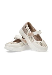 Zapatos blancos perforados con una correa crema, punta redondeada y acentos en un beige claro. Suela blanca acolchada para mayor comodidad, con diseño recortado.