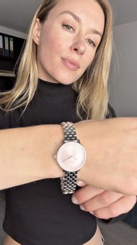 Sølvmetallarmbåndsur med en rund rosa skive og sølvfargede timeindekser, komplettert med et teksturert lenkearmbånd.