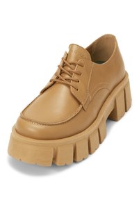 Chaussure en cuir tan à lacets avec un bout arrondi et une semelle épaisse et texturée. Présente des détails de coutures subtils et une finition lisse.
