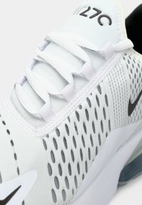 Bijele Nike Air Max 270 tenisice s mrežastom gornjom, točkastom teksturom, ravnim vezicama i sivoj swoosh oznaci. Imaju podložen potplat.