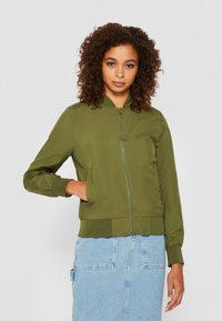 Olivově zelená bomber bunda z lehkého materiálu, s zipovým uzávěrem, ribbenými manžetami a spodním lemem, bočními kapsami a hladkým povrchem.