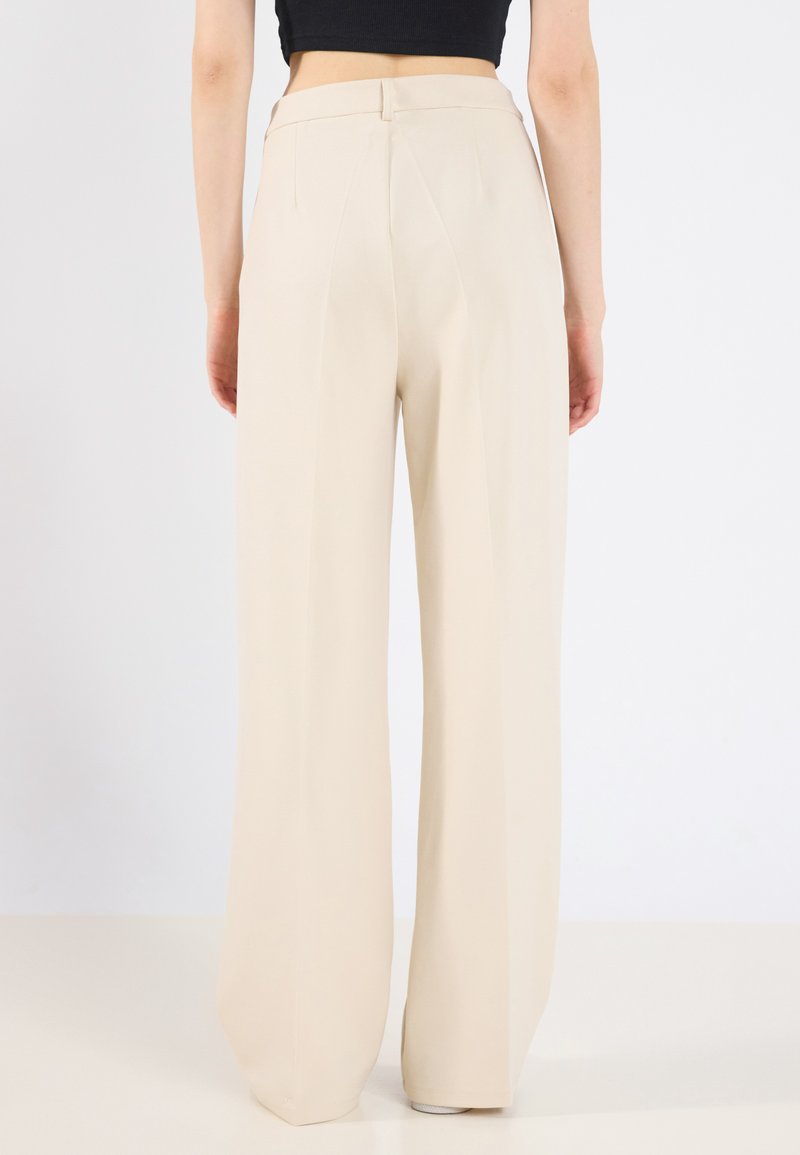 Beige wijde broek van gladde stof, met een hoge taille, plooien aan de achterkant en een nette afwerking aan de zoom.