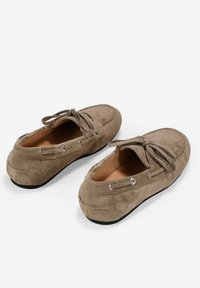 Zapatos de mocasín de ante marrón con cordones, ojales de metal plateado, suelas de goma planas y un forro interior suave.