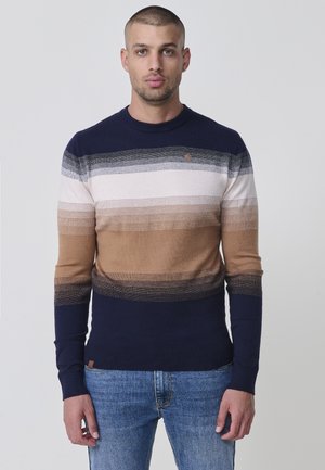 Suéter de punto con rayas horizontales en azul marino, blanco, beige y marrón. Presenta un cuello redondo y puños acanalados. Detalle sutil del logo en el pecho.