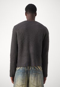 Dunkelgrauer, weicher Wollpullover mit einem leicht verkürzten R�ücken und langen Ärmeln. Verfügt über einen runden Halsausschnitt und eine strukturierte Oberfläche.