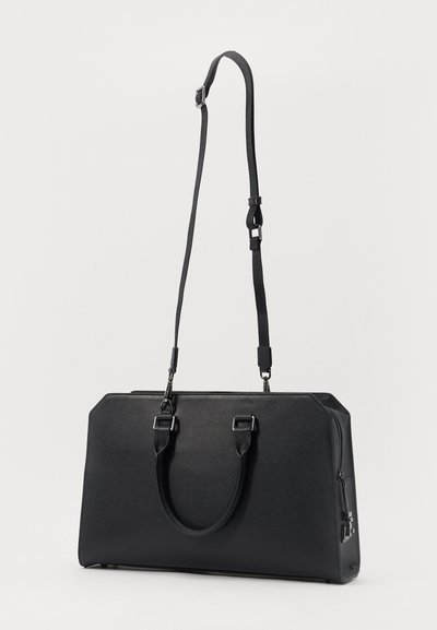 Svart läderhandväska med en strukturerad design, som har ett handtag på toppen och en justerbar axelrem. Slät textur och minimala hårdvarudetaljer.