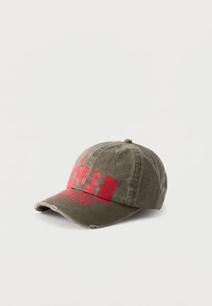 Olive green baseball cap with distressed details and red abstract paint design on the front, displayed on a white background.