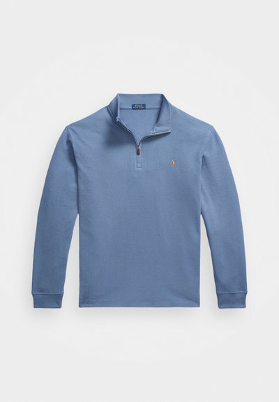 Zils garām piedurknēm polo krekls, kas izgatavots no kokvilnas, ar pus-izsienamu apkakli, ribota piedurkņu gala un mazu izšuvumu uz krūts.