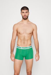 Groene boxershorts met een witte tailleband met groene strepen en het "PUMA" logo. De stof lijkt glad en rekbaar.