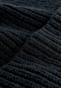 Material textil negru cu un model striat, aspect moale și pufoș, evidențiind nuanțe adânci și o adâncime variată a suprafeței.