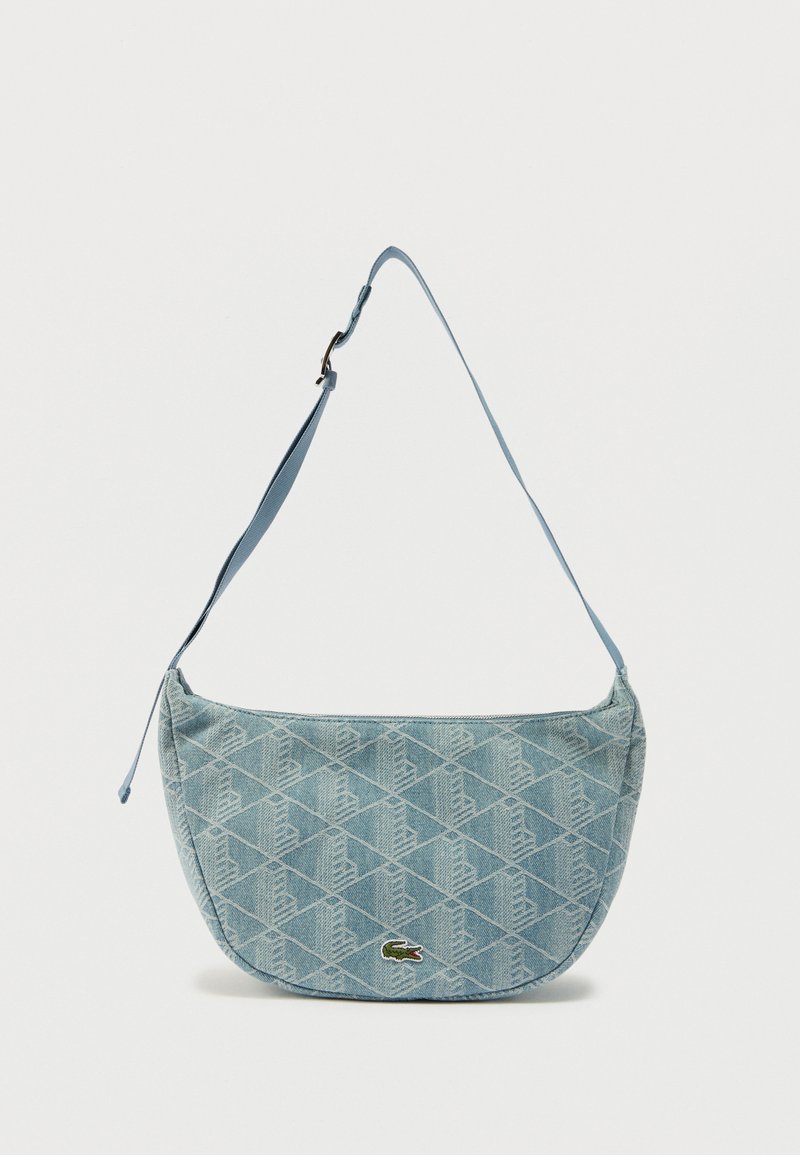 Ανοιχτό μπλε καπιτονέ τσάντα ώμου με ρυθμιζόμενο λουράκι και μικρό πράσινο λογότυπο κροκοδείλου στο κέντρο εμπρός πλευράς.