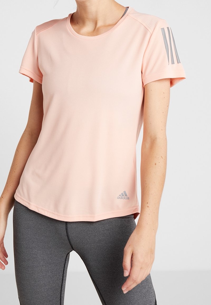 Světle růžové sportovní tričko vyrobené z tkaniny odvádějící vlhkost, s kulatým výstřihem, krátkými rukávy a šedým logem a akcenty Adidas.