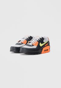Černé a šedé sneakers s oranžovými a žlutými akcenty, s gumovou podrážkou, textilním svrškem a polstrovanou mezipodrážkou s viditelnou vzduchovou jednotkou.