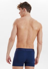 Mörkblå kalsonger i en mjuk, stretchig tyg. Har en åtsittande passform med ett kontrasterande midjeband och minimala sömmar för komfort.