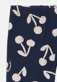 Blaue Leggings mit einem weißen Kirschmuster. Verfügt über einen elastischen Bund und einen weichen, strukturierten Stoff. Geeignet für Freizeitkleidung.