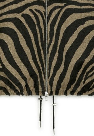 Kledingstuk met zebrapatroon in zwart en tan. Voorzien van een zilverkleurige rits in het midden en trekkoorden met metalen accenten.