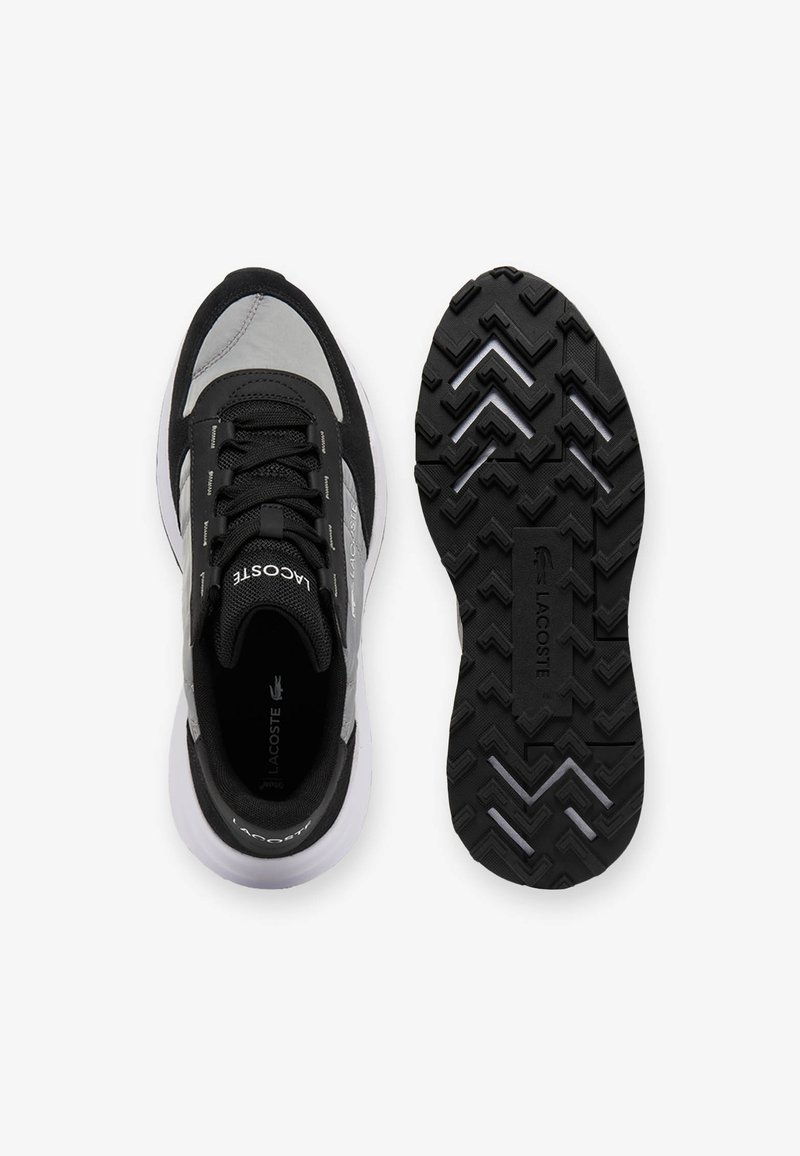 Baskets montantes noires et grises, vues du dessus et de la semelle, avec une semelle texturée aux motifs angulaires et le logo Lacoste sur la languette et la semelle.