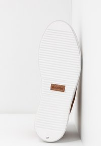 Brown suede shoe with a white rubber sole featuring horizontal grooves and a branded leather patch labeled "BLACKSTONE." Size 37 visible.