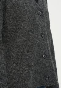Grau gestrickte Strickjacke mit strukturiertem Finish, V-Ausschnitt, schwarzen Knopfverschlüssen und einer leicht lockeren Passform.