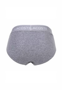 Sous-vêtements en coton gris avec une ceinture douce ornée du logo "LACOSTE". Texture lisse et couverture complète du dos avec des bords arrondis.