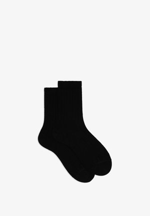 Calzini in cotone neri con trama a costine e lunghezza fino a metà polpaccio. Presentano un polsino morbido ed elastico per il comfort.