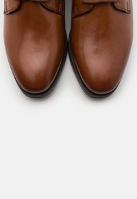 Chaussures en cuir marron à finition lisse, avec un bout arrondi et des fermetures à sangle réglables. Semelle en caoutchouc noir solide.
