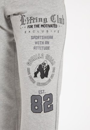 Grijze sweats met een zachte textuur, voorzien van zwarte bedrukte graphics, waaronder een gorilla-logo, tekst en het nummer "82."