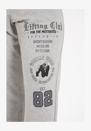 Grijze sweats met een zachte textuur, voorzien van zwarte bedrukte graphics, waaronder een gorilla-logo, tekst en het nummer "82."