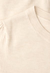 Pull en maille douce de couleur crème avec encolure ronde côtelée et léger détail bouffant sur la couture de l'épaule.