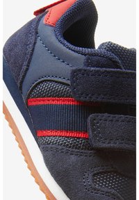 Marinblå sneakers med mocka och mesh-material, röda detaljer och kardborreband. Gummisula med texturerat grepp. Kompakt design.