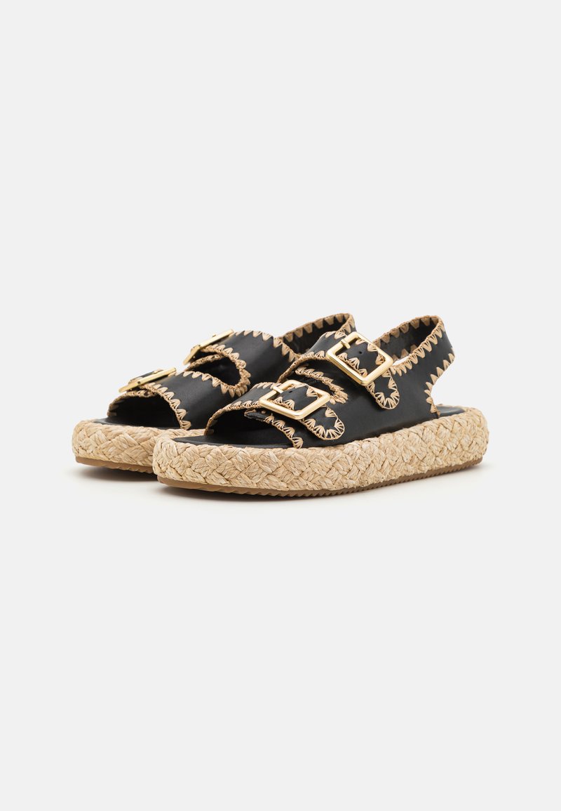 Schwarze Leder-Sandalen mit doppelten Schnallenriemen, geflochtener Jutesohle, dekorativen Nähten und offenem Zehenbereich.