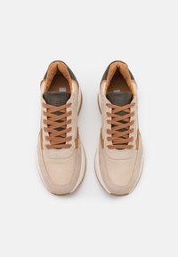 Scarpe sportive beige e marrone caratterizzate da una combinazione di suede testurizzato e pelle liscia. Forma arrotondata con chiusura a lacci e colletto imbottito.