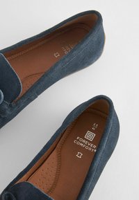 Tummansininen mokkanahka loaferit pyöreällä varvalla, sileällä vuorella ja pehmeällä pohjalla, jossa on pieniä reikiä hengittävyyden parantamiseksi.