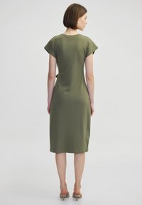 Olivgrünes, knielanges Kleid mit kurzen Cap-Ärmeln, einem runden Ausschnitt und einem lockeren Schnitt. Das Material scheint weich mit einer glatten Textur zu sein.