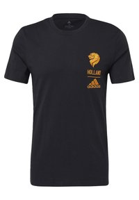Černé bavlněné tričko s krátkým rukávem. Obsahuje grafiku oranžového lva, text "HOLLAND" a logo adidas na hrudi. Jednoduchý, ležérní design.
