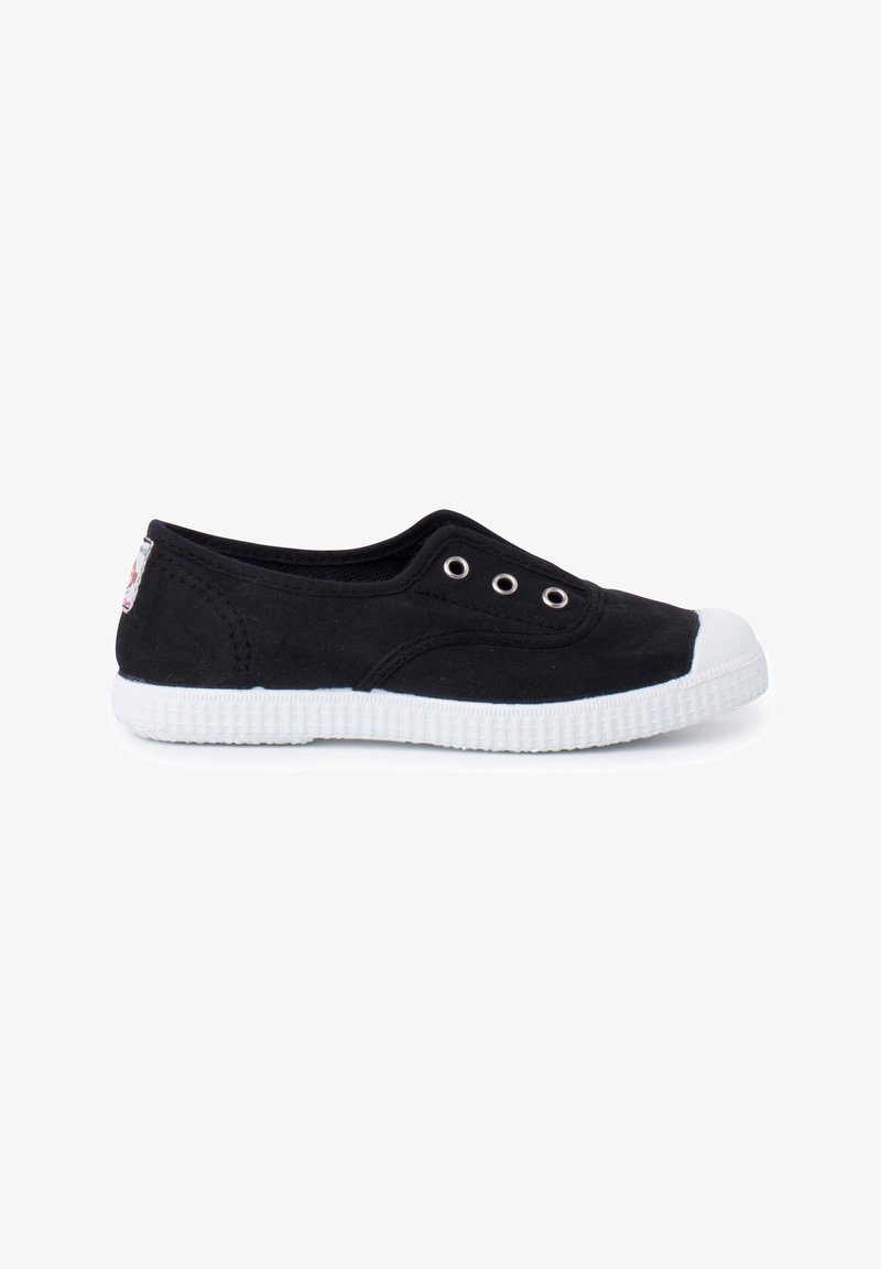 Chaussure slip-on basse noire en toile avec semelle et embout en caoutchouc blanc, présentant trois œillets métalliques et des détails de couture minimaux.