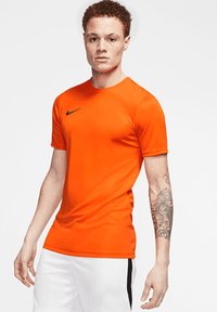 Maglietta sportiva arancione con scollo rotondo e maniche corte, impreziosita da un logo Nike nero sul petto. Tessuto morbido e design aderente.