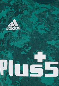 Zelený sportovní dres s texturovaným, maskáčovým vzorem; obsahuje bílé logo "adidas" a „Plus5“ v tučném, bílém písmu.