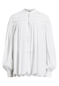 Camicia bianca con collo alto, chiusura frontale con bottoni e maniche lunghe a sbuffo. Presenta dettagli arricciati e un orlo smerlato. Composta in un tessuto leggero.
