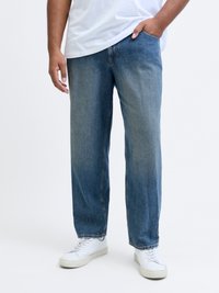 Heledad sinise värviga teksapüksid, millel on relaxed fit, sirged sääred, nähtavad õmblused ja kerge pleekimine. Kombineeritud valgete tossudega.