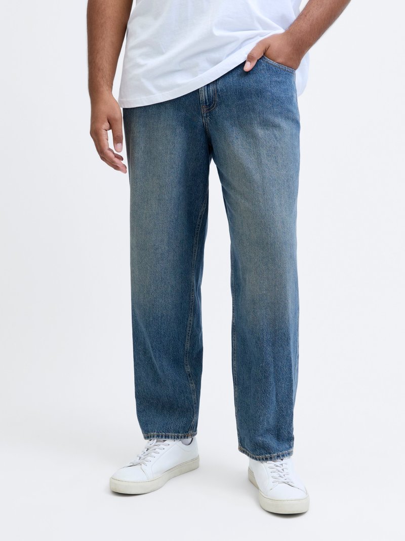 Heledad sinise värviga teksapüksid, millel on relaxed fit, sirged sääred, nähtavad õmblused ja kerge pleekimine. Kombineeritud valgete tossudega.