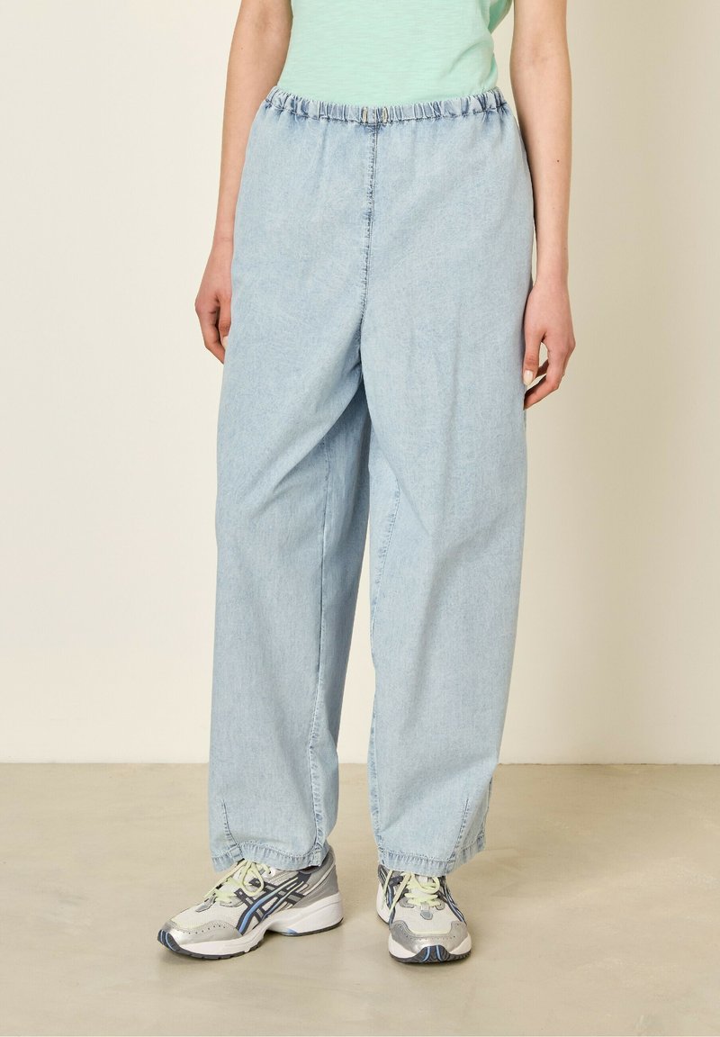 Ljusblå, vida jeans med elastisk midja. Tyget har en mjuk textur och fållarna är något gathers.