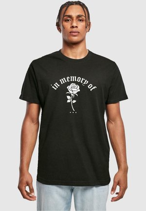 Black cotton t-shirt featuring white text reading "in memory of" above a detailed rose graphic. Short sleeves and standard fit.