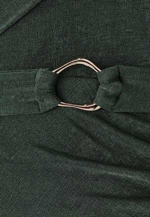Dark green fabric with a textured pattern, featuring a knotted detail and a silver circular hardware accent.