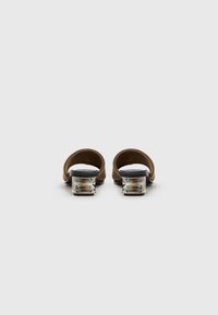 Brown open-toe mules with a transparent heel. The upper is smooth, while the sole has a contrasting black edge.