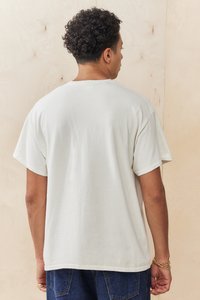 Relaxed-fit, crew-neck t-shirt in off-white cotton, featuring short sleeves and a plain back design. No graphics or patterns visible.
