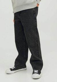 Svarta denimjeans med rakt ben-design, med synlig sömnad och sidofickor, i kombination med svartvita sneakers.