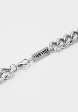 Zilveren schakelarmband met een rechthoekige plaat gegraveerd met "WFTW" en een karabijnsluiting op een witte achtergrond.